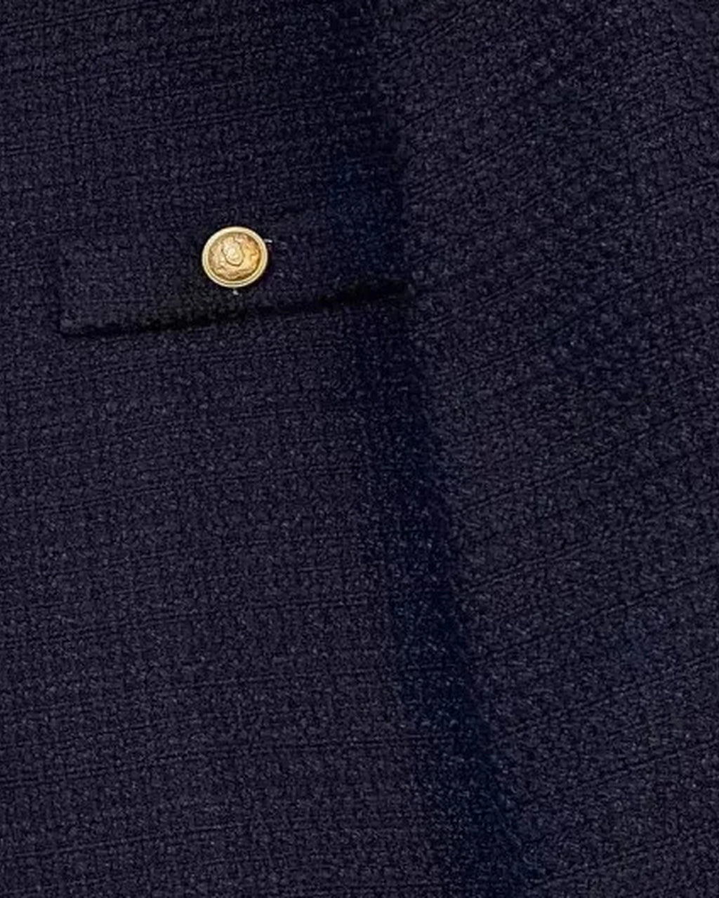 Navy textured weave and gold-tone button on the flap pocket, close-up