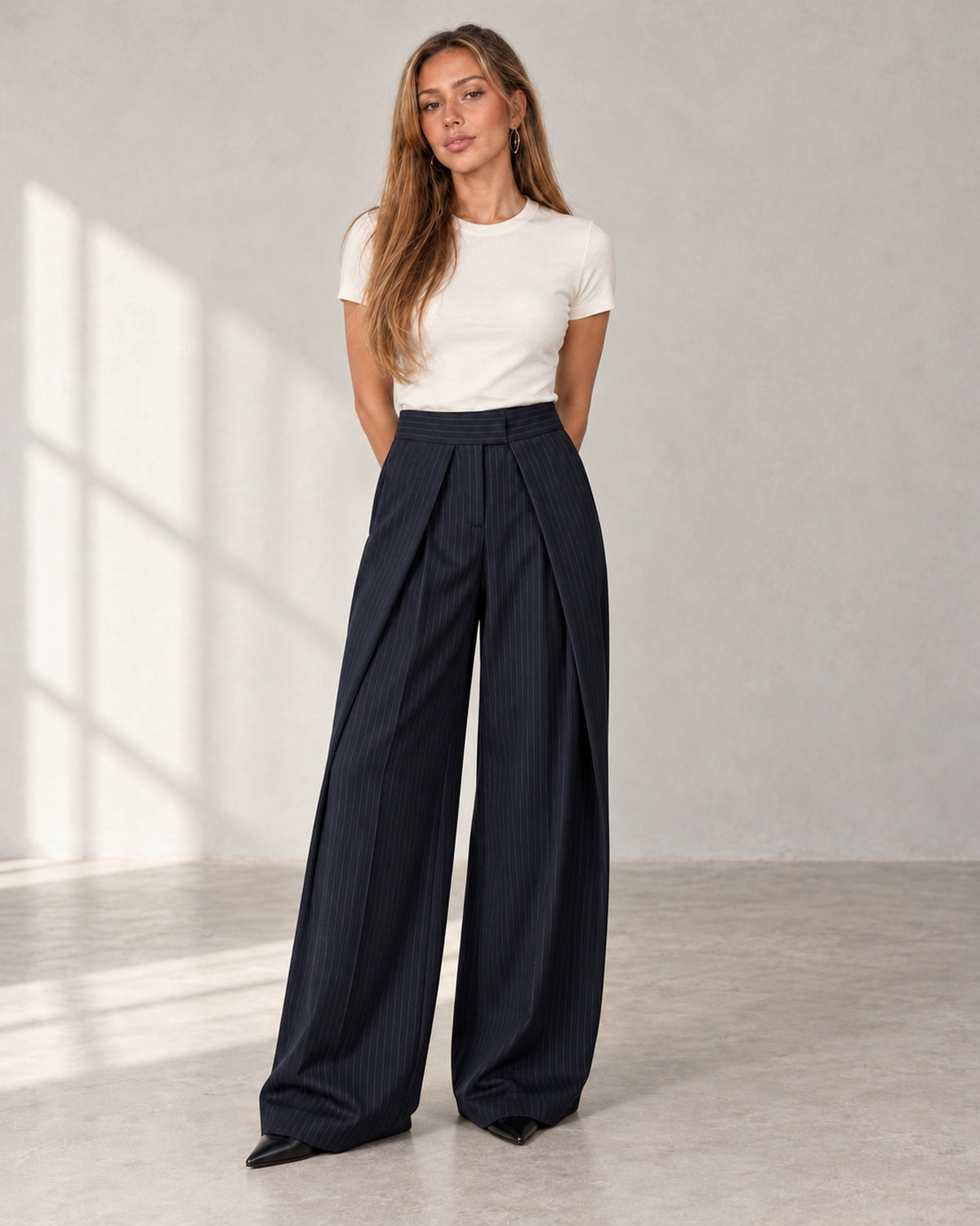 Pleated wide-leg trousers in navy pinstripe, worn by a model